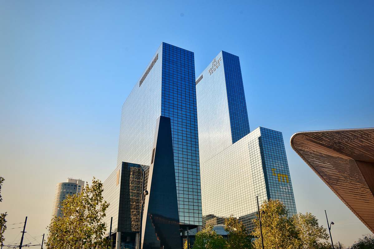 city glass walled high-rise buildings near green trees under blue skies building